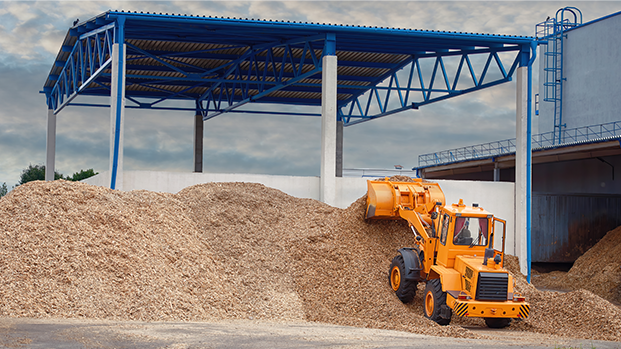 An orange backhoe picking up mulch