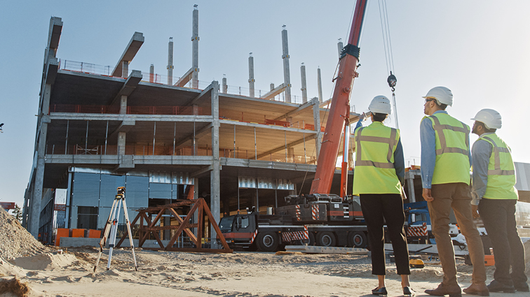 Photo of construction workers looking at building being built