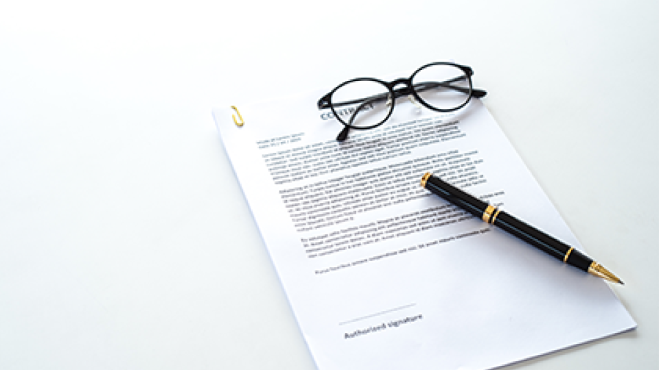 Stock photo of a document with glasses and a pen atop