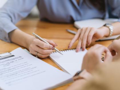 Hands writing on notepad within office