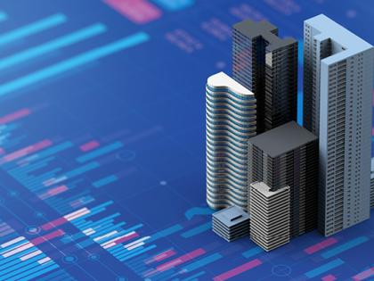 A group of model buildings sit on top of some stock-related charts