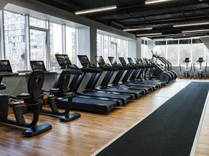 A gym with rows of treadmills and large windows