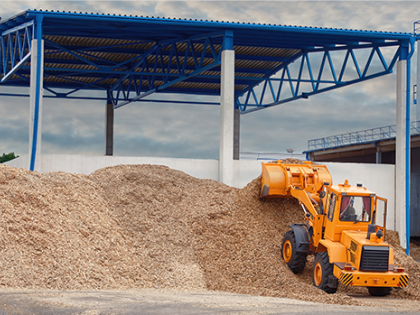 An orange backhoe picking up mulch