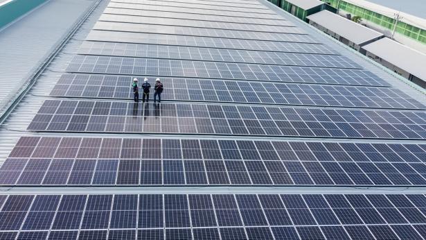 Men working on flat rooftop CareySolar solar panels to represent the benefits of green leasing for net leased properties
