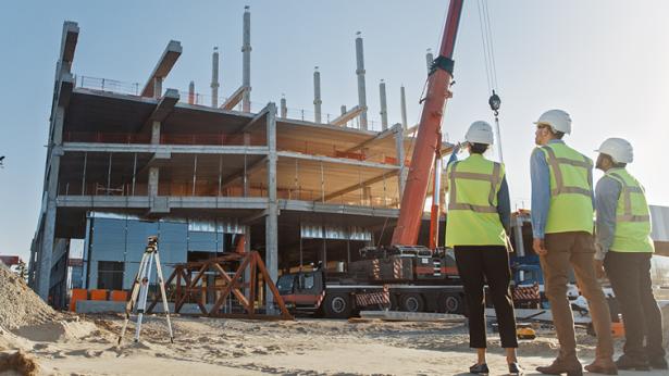 Photo of construction workers looking at building being built