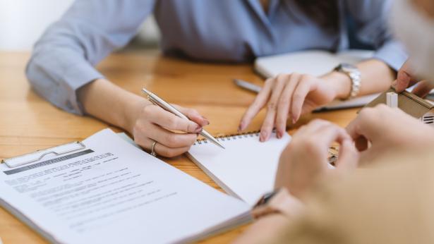 An unrecognizable person showing another person where to sign after they decided between the different lease types.