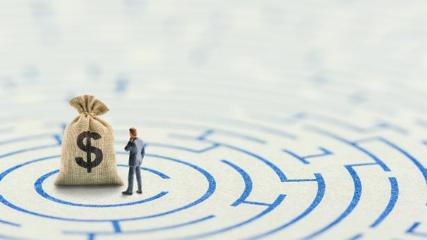 Man and money bag in a maze to represent financial stress, which can be eased by W. P. Carey's sale leasebacks or alternative financing methods