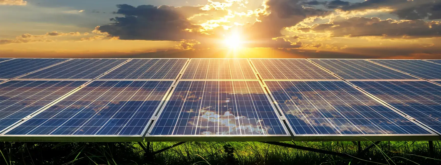 Solar panels on a grassy field at sunset