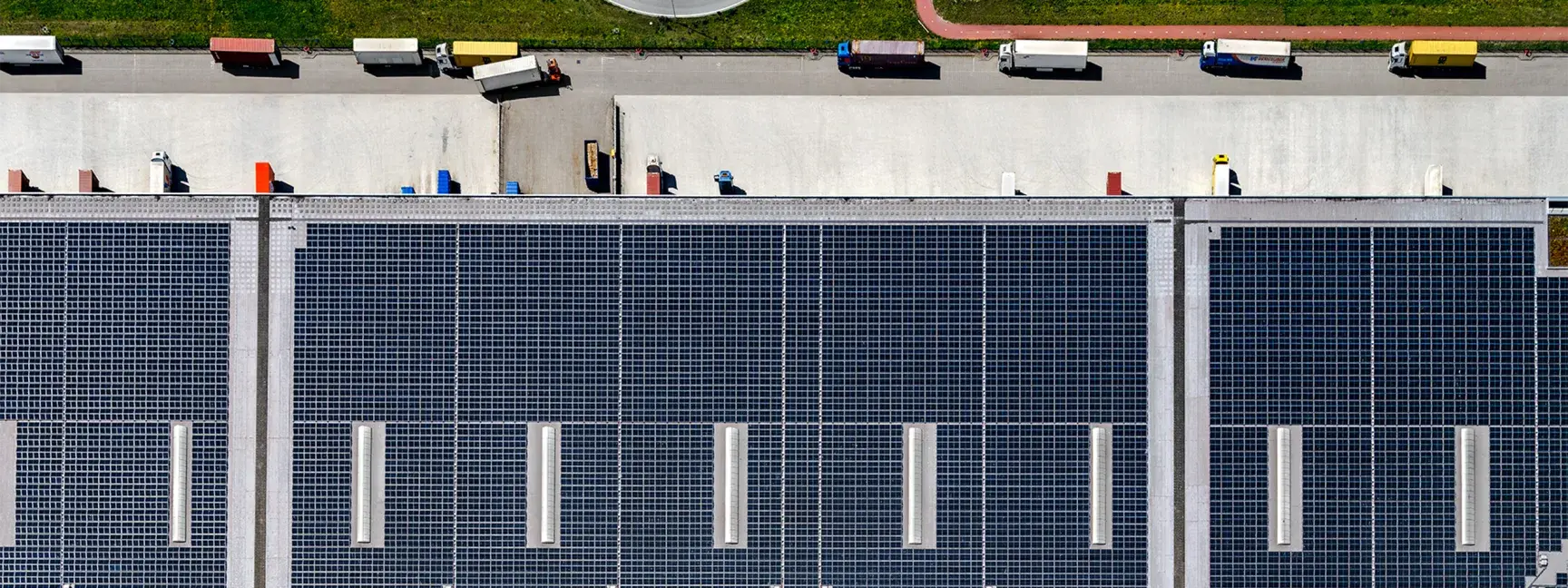 Aerial shot of a warehouse with lots of trucks lined up and solar panels on the entire roof