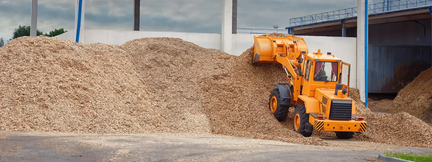 An orange backhoe picking up mulch