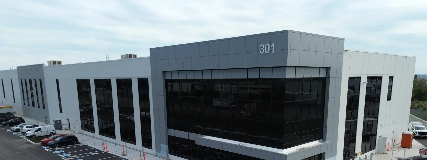 Exterior of a white industrial facility with large windows.